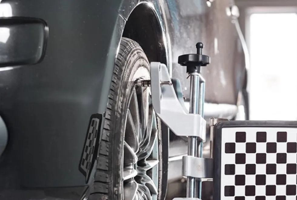 Close-up of a wheel alignment clamp and target mounted on a car wheel