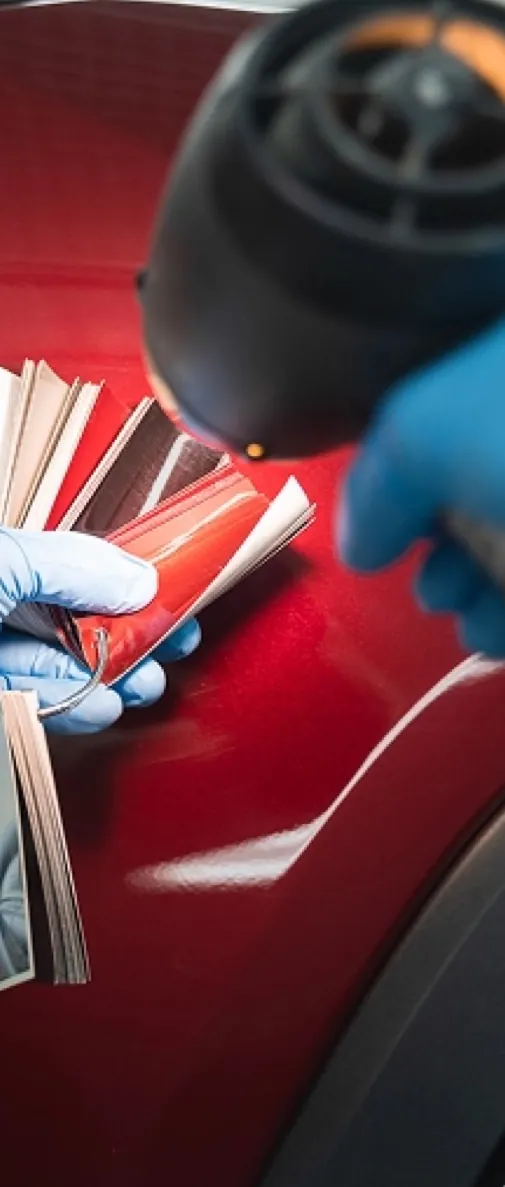 Paint color swatches held against a glossy red car panel