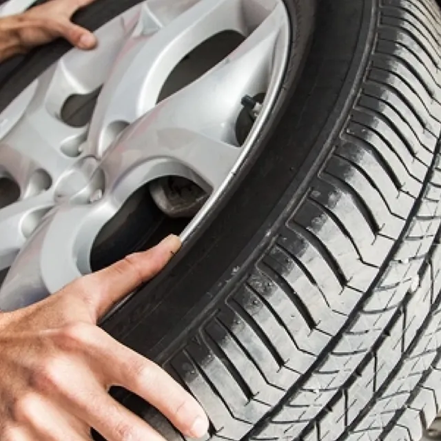 Two hands holding a tire and alloy wheel